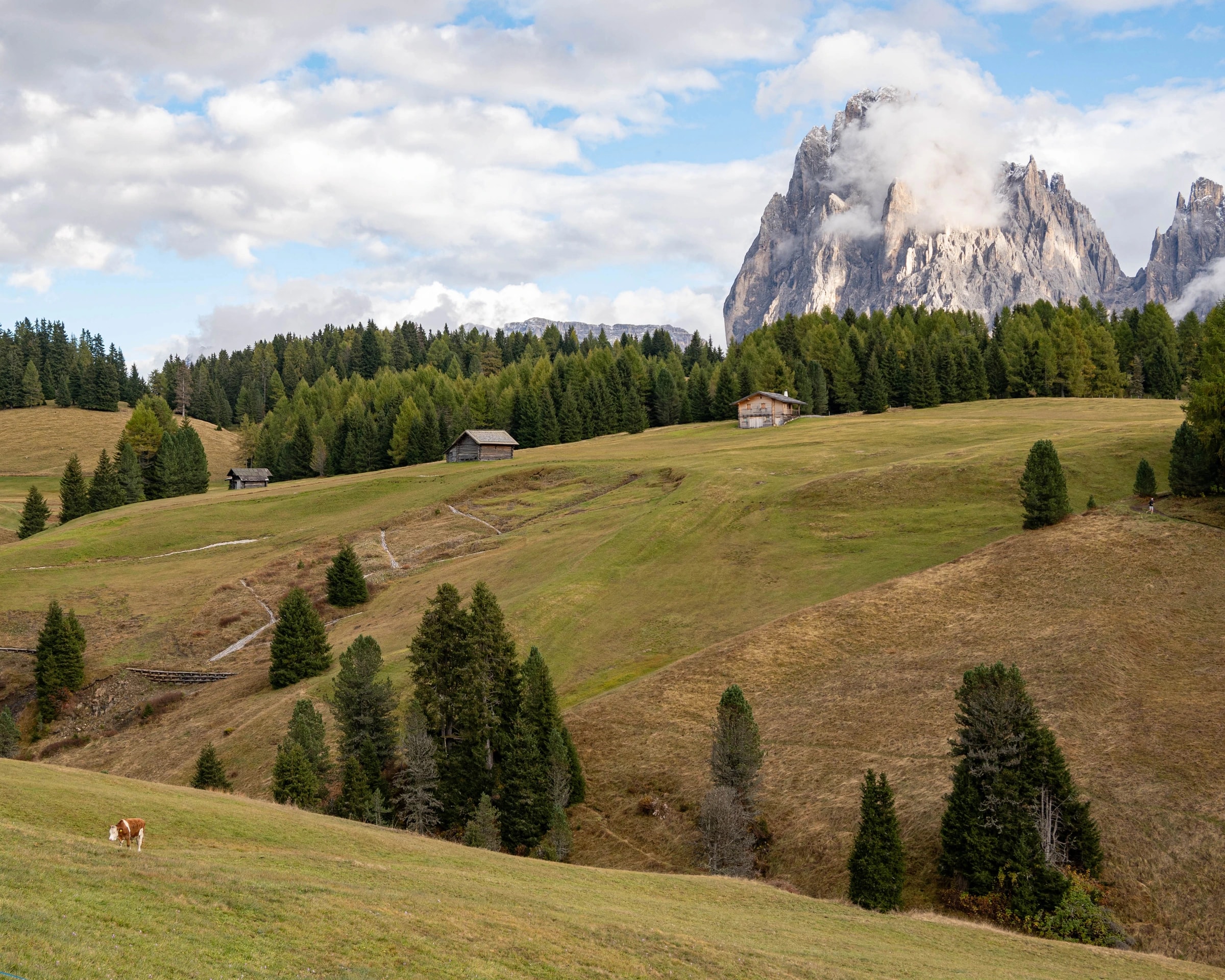 Sweeping view of the Italian Dolomites at sunset, jagged peaks lit warm against deepening sky.