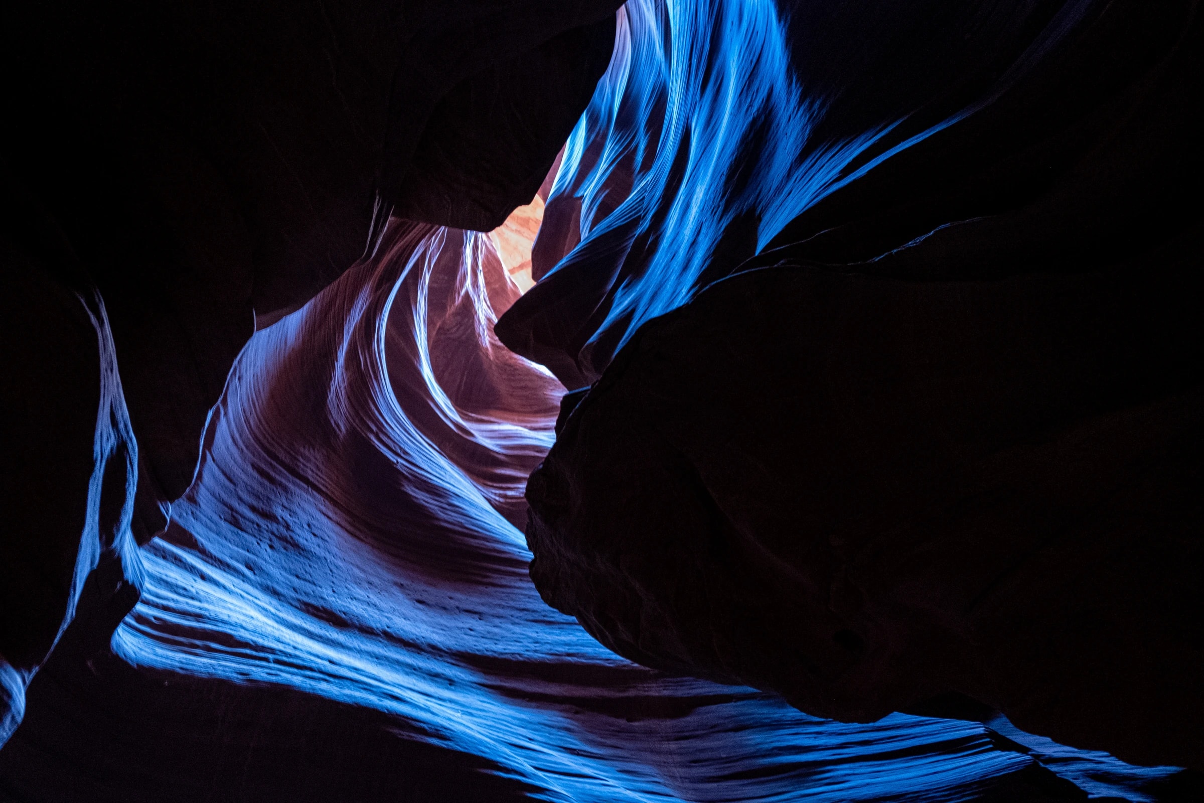 Sandstone slot canyon walls in deep blue and red, light streaming from above.